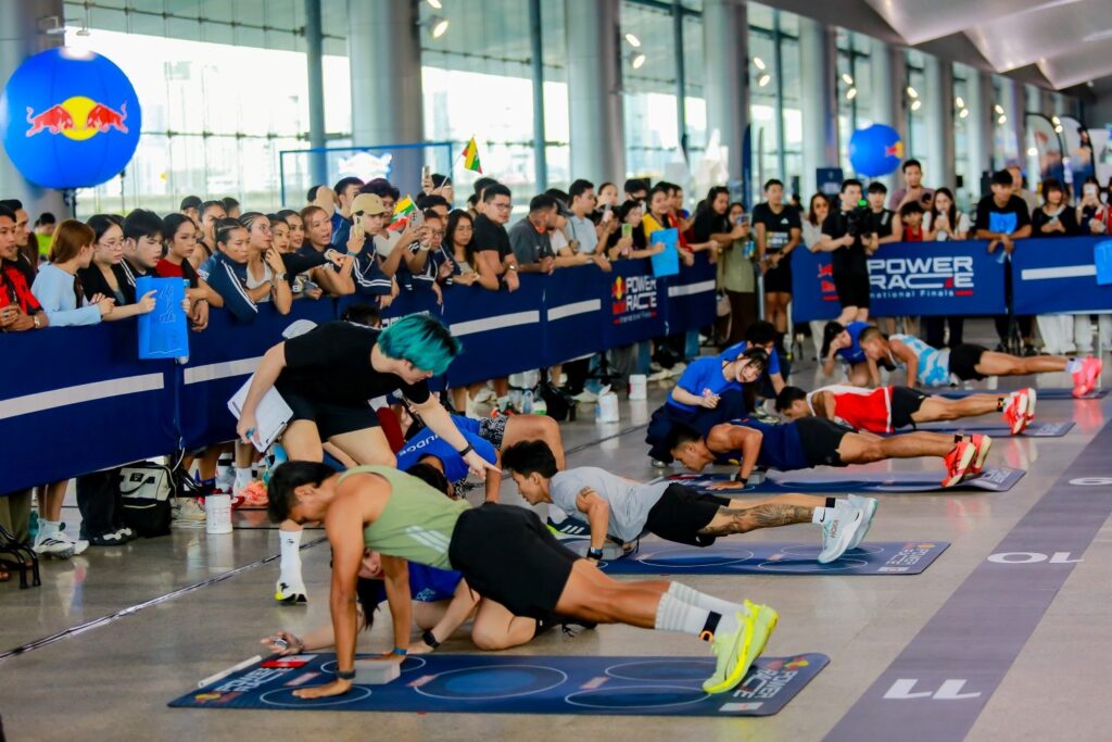 Athletes complete push-ups at an exercise station as judges count repetitions